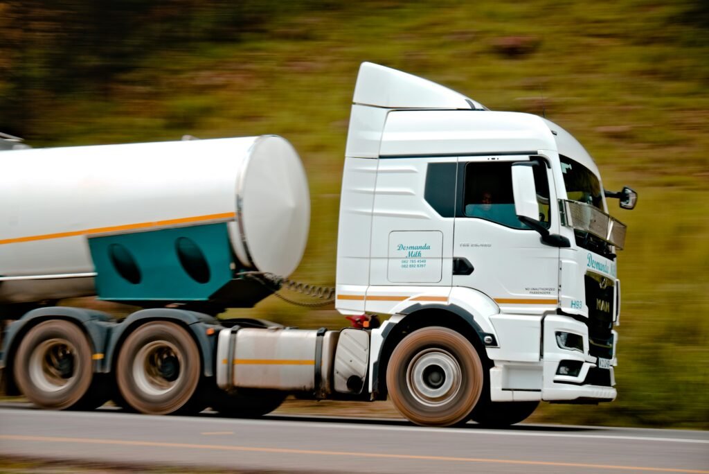 Close-up of a fast-moving white tanker truck on a highway, capturing motion and speed.